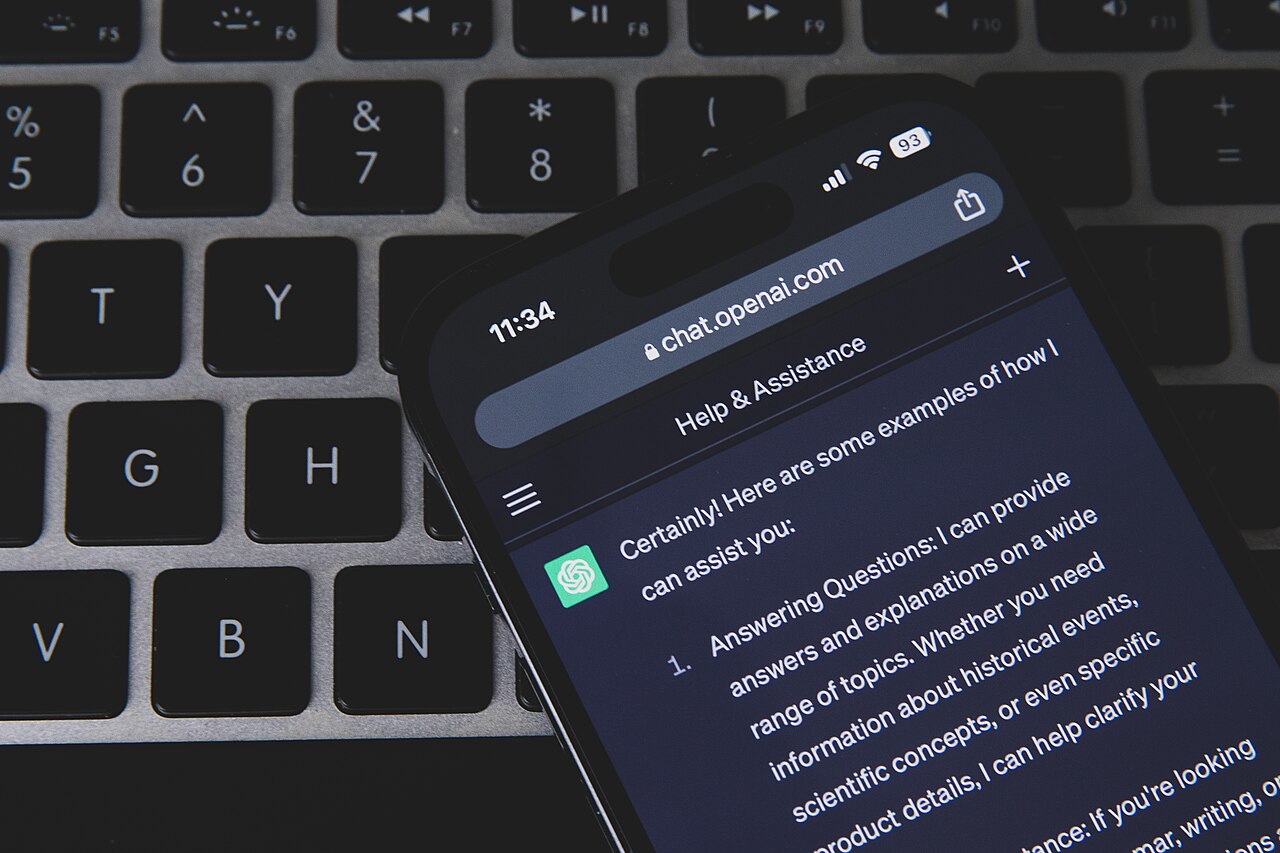 Un smartphone posé en diagonale sur un clavier affiche une conversation avec ChatGPT.