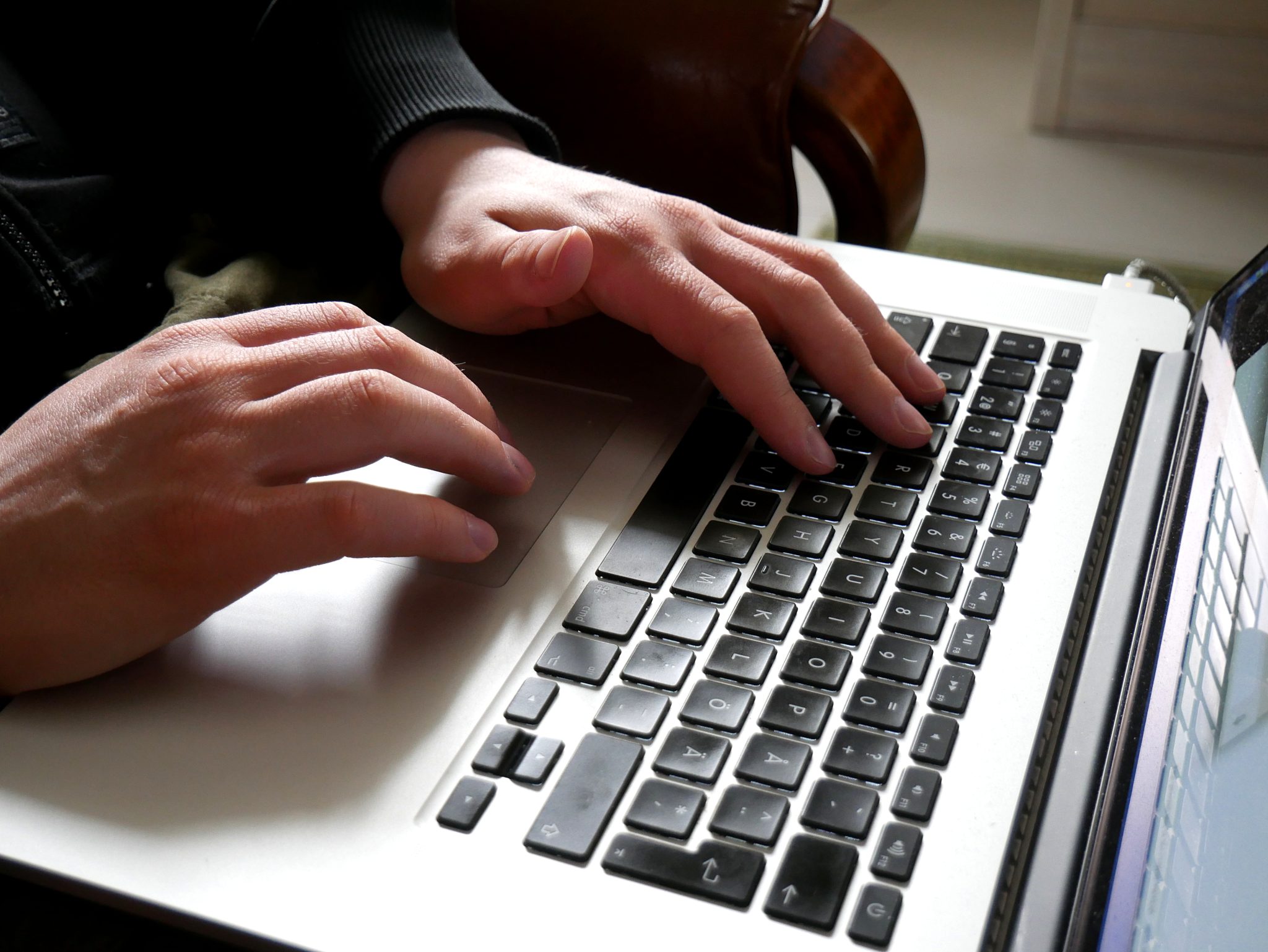 Des mains utilisent le clavier et le pavé tactile d'un ordinateur portable.